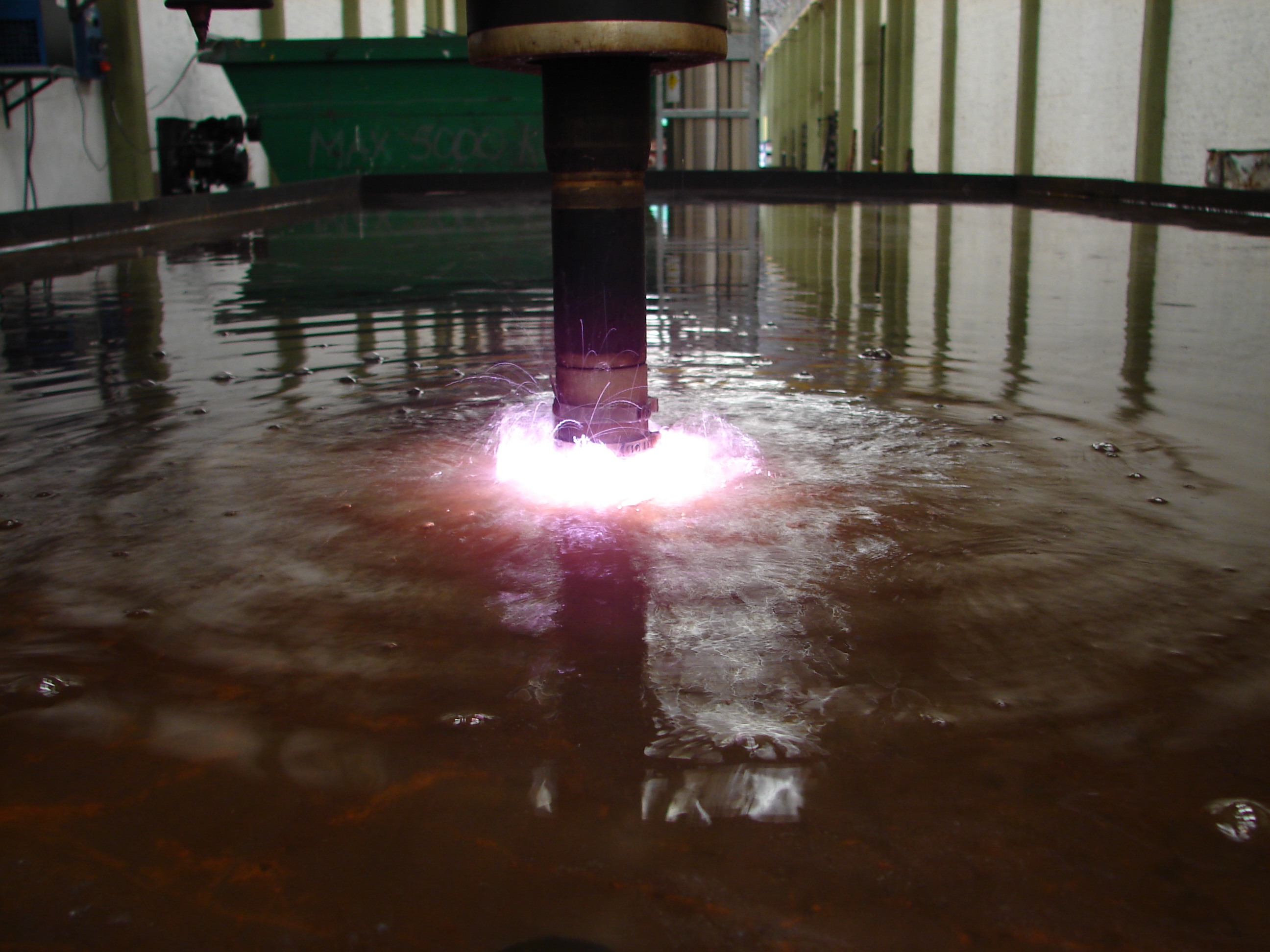 Plasma cutting operation showing bright arc and metal cutting